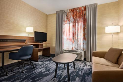 a hotel room with a couch and a desk and a television at Fairfield Inn & Suites by Marriott Hershey Chocolate Avenue in Hershey