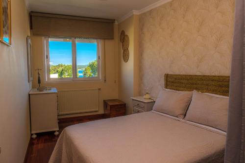 um quarto com uma cama branca e uma janela em El balcón de Barraña em Boiro