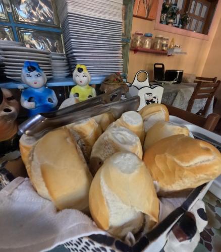 a table topped with lots of different types of bread at Pousada Pedacinho de Céu in Abraão