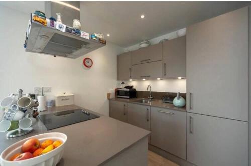 a kitchen with a bowl of fruit on a counter at Room with private bathroom in a modern two bedroom two bathroom flat in London