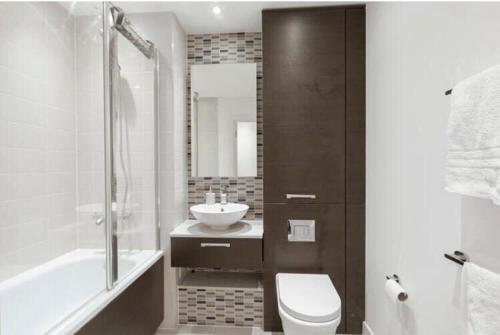 a bathroom with a sink and a toilet and a tub at Room with private bathroom in a modern two bedroom two bathroom flat in London