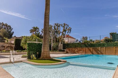 een zwembad met een palmboom in een tuin bij Tamanaco Beach 1BDR apartment with balcony sea view and pool in Antibes