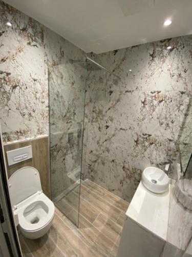 La salle de bains est pourvue de toilettes et d'une douche en verre. dans l'établissement EQ Tirana Apartments, à Tirana