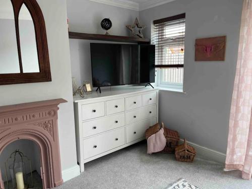 a living room with a television and a dresser with a fireplace at Bright and Cosy Home in Southend-on-Sea