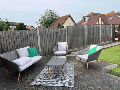 a patio with three chairs and a table and a fence at Bright and Cosy Home in Southend-on-Sea