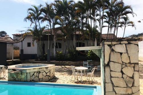 ein Haus mit einem Pool und Palmen in der Unterkunft Casa de campo com piscina, mesa de bilhar e 3 quartos in Itanhandu