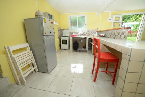 a kitchen with a refrigerator and red chairs in it at Maison LAVANNE in Saint-Joseph