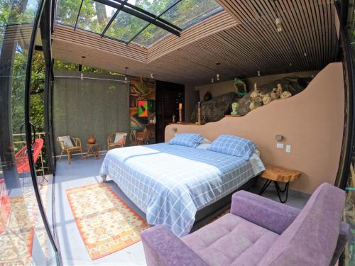 a bedroom with a bed and two purple chairs at Eco Lodge Macabaña Rupestre in La Mesa