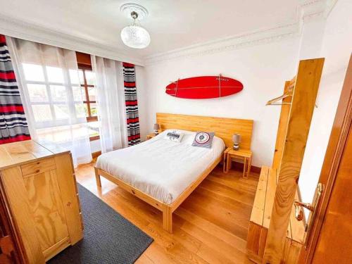 um quarto com uma cama e uma prancha de surf vermelha na parede em La Casa de Enzo em Argoños