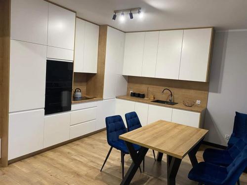 a kitchen with a wooden table and blue chairs at Nowoczesny Apartament Królowej Jadwigi in Radom