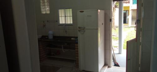 uma cozinha com um frigorífico branco num quarto em Casa na beira da Praia Cumuruxatiba em Cumuruxatiba
