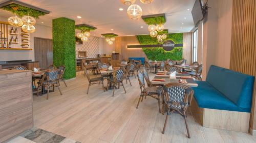 a restaurant with tables and chairs and a green wall at REEC Machala by Oro Verde Hotels in Machala