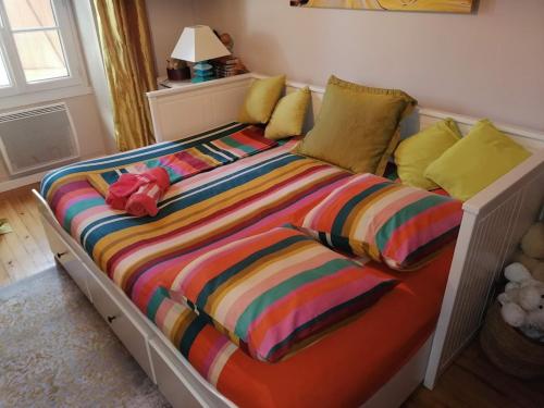 uma cama com um edredão listrado colorido e almofadas em Trois Chambres d'Hôtes dans charmante longère Charentaise 