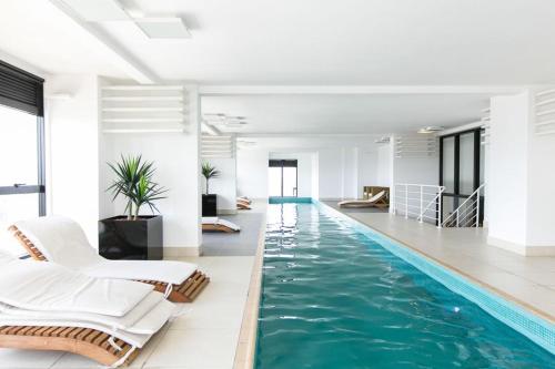 a swimming pool with chairs and a swimming pool at Dois quartos, lindo, garagem, Condomínio Clube Sky in Curitiba