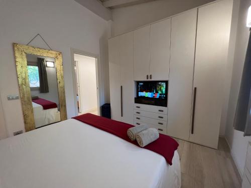 a white bedroom with a large bed and a television at Antica Fonte Holiday Homes in San Pantaleo