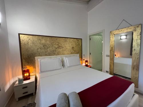 a bedroom with a large white bed and a mirror at Antica Fonte Holiday Homes in San Pantaleo
