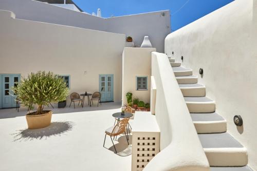 Biały dom z białymi ścianami i białymi schodami w obiekcie Arxegono Cave Houses Santorini w mieście Pirgos