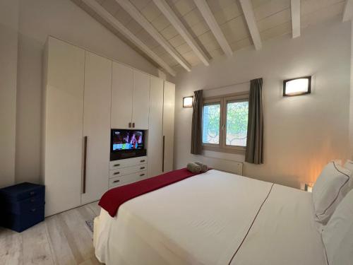 a bedroom with a large white bed and a television at Antica Fonte Holiday Homes in San Pantaleo