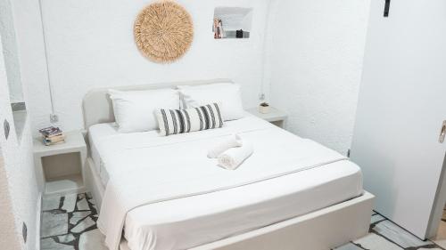 a white bedroom with a white bed with black and white pillows at White Haven Cave Home in Mesaria