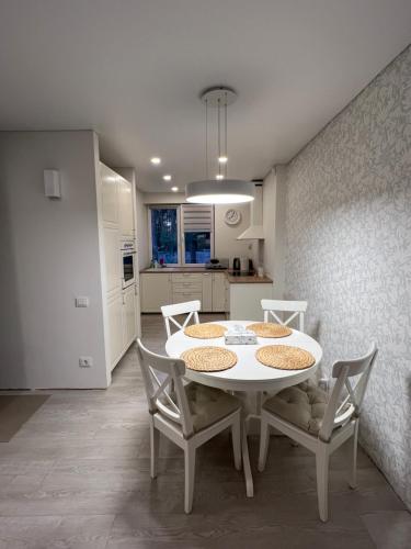 eine Küche und ein Esszimmer mit einem weißen Tisch und Stühlen in der Unterkunft Palūšės Apartment in Palūšė