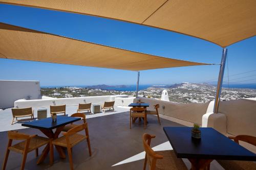 a view from the roof of a restaurant with tables and chairs at Arxegono Cave Houses Santorini in Pirgos