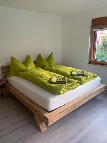 Cama con almohadas verdes en una plataforma de madera en B&B Kalbermatter, en Turtmann