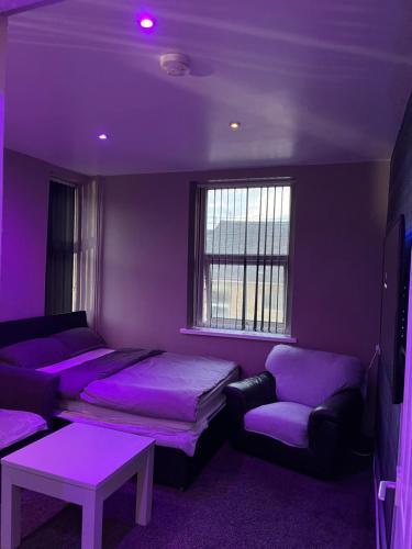 a purple room with two beds and a couch at One Bed Studio Apartment 
