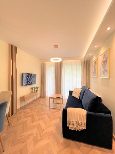 a living room with a black couch and a television at Apartament Chabrowy ( centrum, garaż ) in Kielce