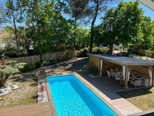 une cour avec une piscine et une pergola dans l'établissement Villa du Bois de la Fontaine, 4 étoiles, avec grande piscine privée, à Moliets-et-Maa