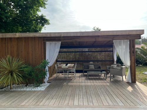 une pergola en bois avec des chaises et des tables sur une terrasse dans l'établissement Villa du Bois de la Fontaine, 4 étoiles, avec grande piscine privée, à Moliets-et-Maa