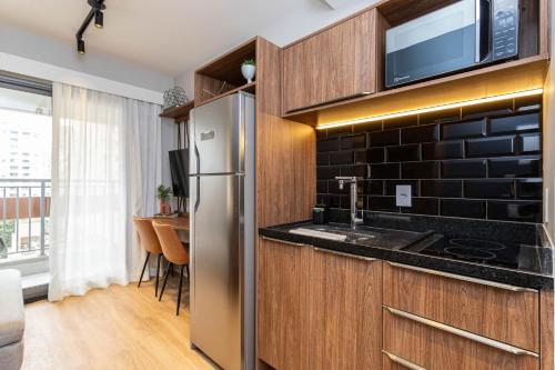 uma cozinha com um frigorífico de aço inoxidável e um micro-ondas em Charlie Hotel Atmosfera Paulista em São Paulo