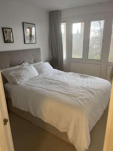 a white bed in a bedroom with two windows at Experience Torridon House Maida Vale in London