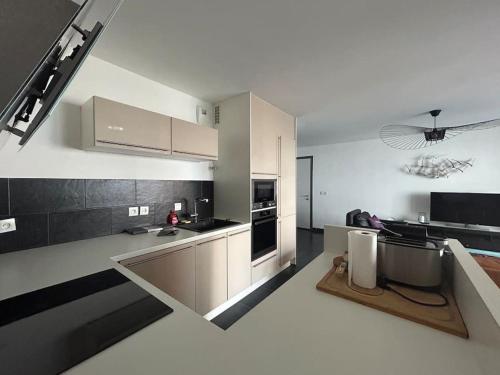 - une cuisine avec des armoires blanches et des appareils en noir et blanc dans l'établissement Le Spinnaker - T3 hyper centre, à Annemasse