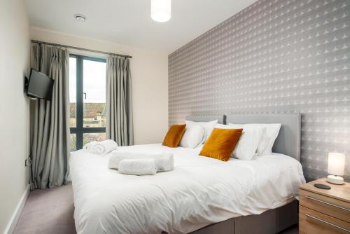 a bedroom with a large white bed with orange pillows at Solar Sanctuary- Skyline Balcony, City Centre, Three Floors, King Beds, Netflix and more! in Bath