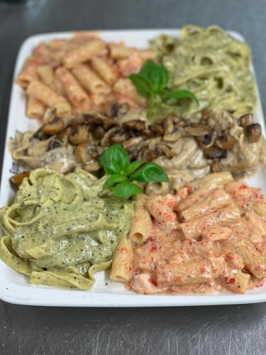 a white plate of food with pasta and vegetables at Hotel Restaurant Zum Landmann in Wenden