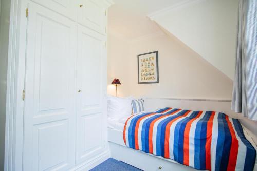 a white bedroom with a bed with a striped blanket at Haus-Moin in Munkmarsch