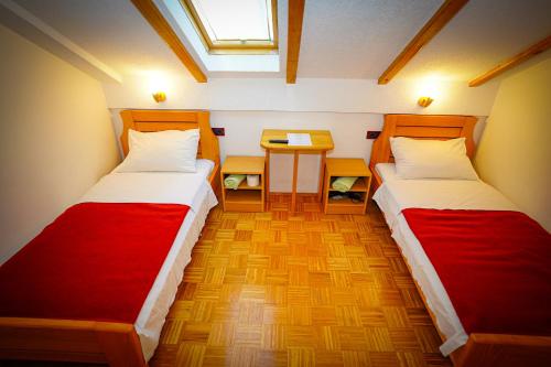 two beds in a room with a table and a window at Apartman Miramare in Otočac