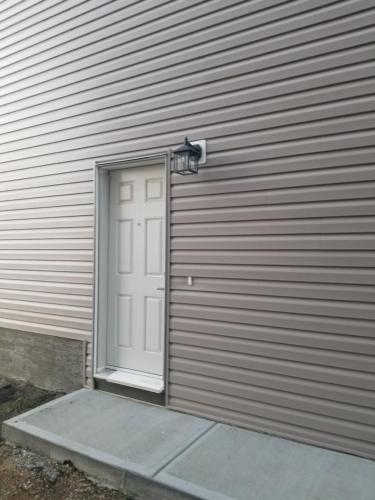 a garage door with a white door and a light at Newcastle. A Place you can call home in Edmonton