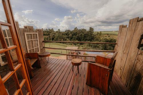 una terraza de madera con mesa y taburetes. en Pousada Campeira, en Brotas