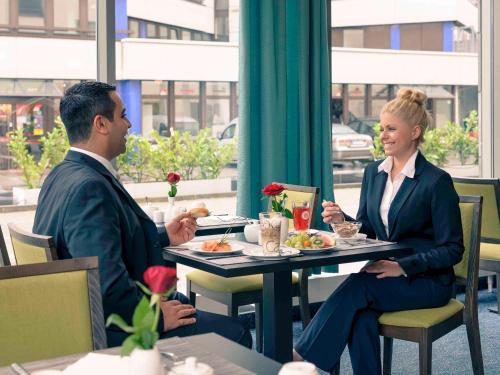 Mercure Hotel Frankfurt Eschborn Süd في إشبورن: يجلس رجل وامرأة على طاولة في مطعم