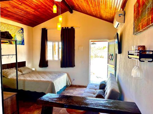 a bedroom with a bed and a couch in a room at Chalé Uyuni in Alto Paraíso de Goiás