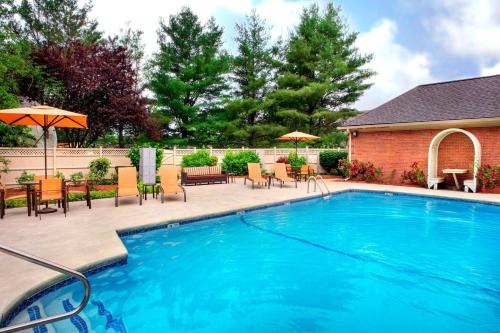 a swimming pool with chairs and tables and umbrellas at Sonesta Select Boston Danvers in Danvers