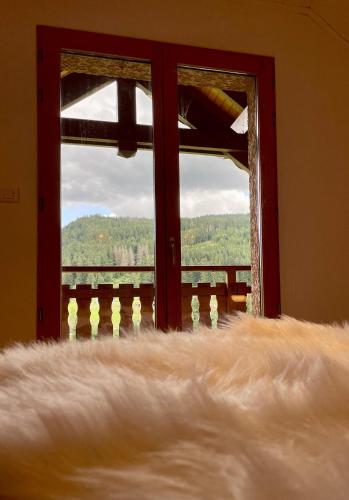 a view of a window with a white blanket looking out at La Gouleote Spacieuse maison type chalet avec jacuzzi, sauna, pétanque in Gérardmer