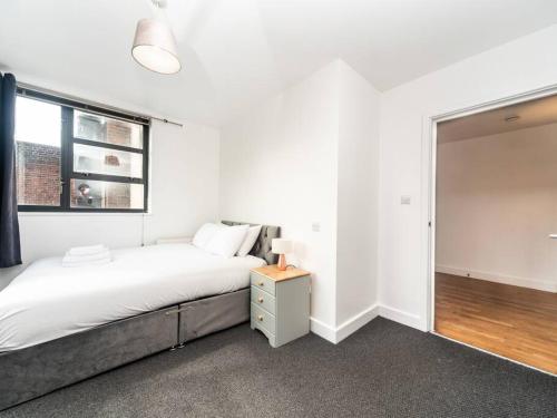 Bright Modern 2 Bed Apartment in East London في لندن: غرفة نوم بيضاء بها سرير ونافذة