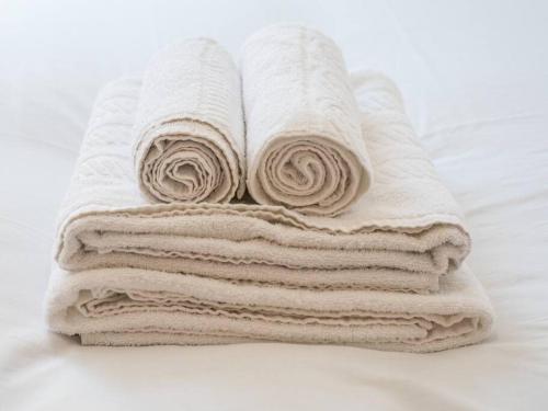 a stack of white towels sitting on a bed at Bright Modern 2 Bed Apartment in East London in London