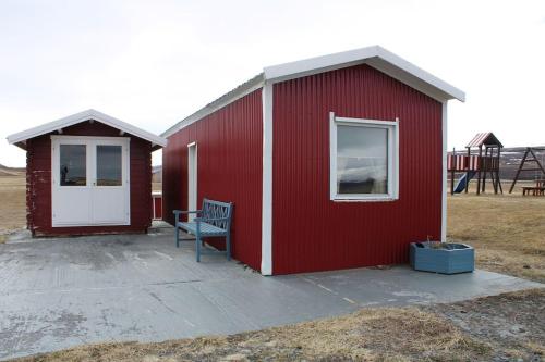 un edificio rojo con un banco delante de él en Stóri-Bakki, cottage Dvergabakki, en Stóri-Bakki