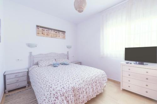 a white bedroom with a bed and a flat screen tv at Villa Julia in Riumar