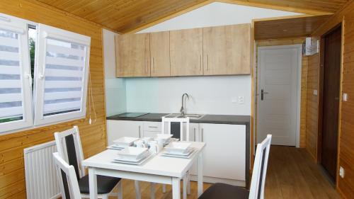 kuchnia i jadalnia z białym stołem i krzesłami w obiekcie Bungalow Camping Jacuzzi & Sauna w Solinie