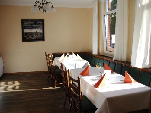 a dining room with white tables and chairs and a window at Apart Hotel Sarstedter Hof in Sarstedt