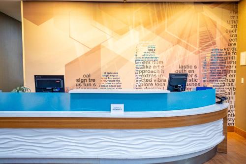 um lobby com um balcão azul e uma parede com palavras em SpringHill Suites by Marriott Baton Rouge Gonzales em Gonzales